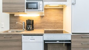 A modern kitchen with a microwave, coffee maker, dishwasher, and oven. - Skivillas 61 ukkohalla (b3) by Interhome (Hyrynsalmi)