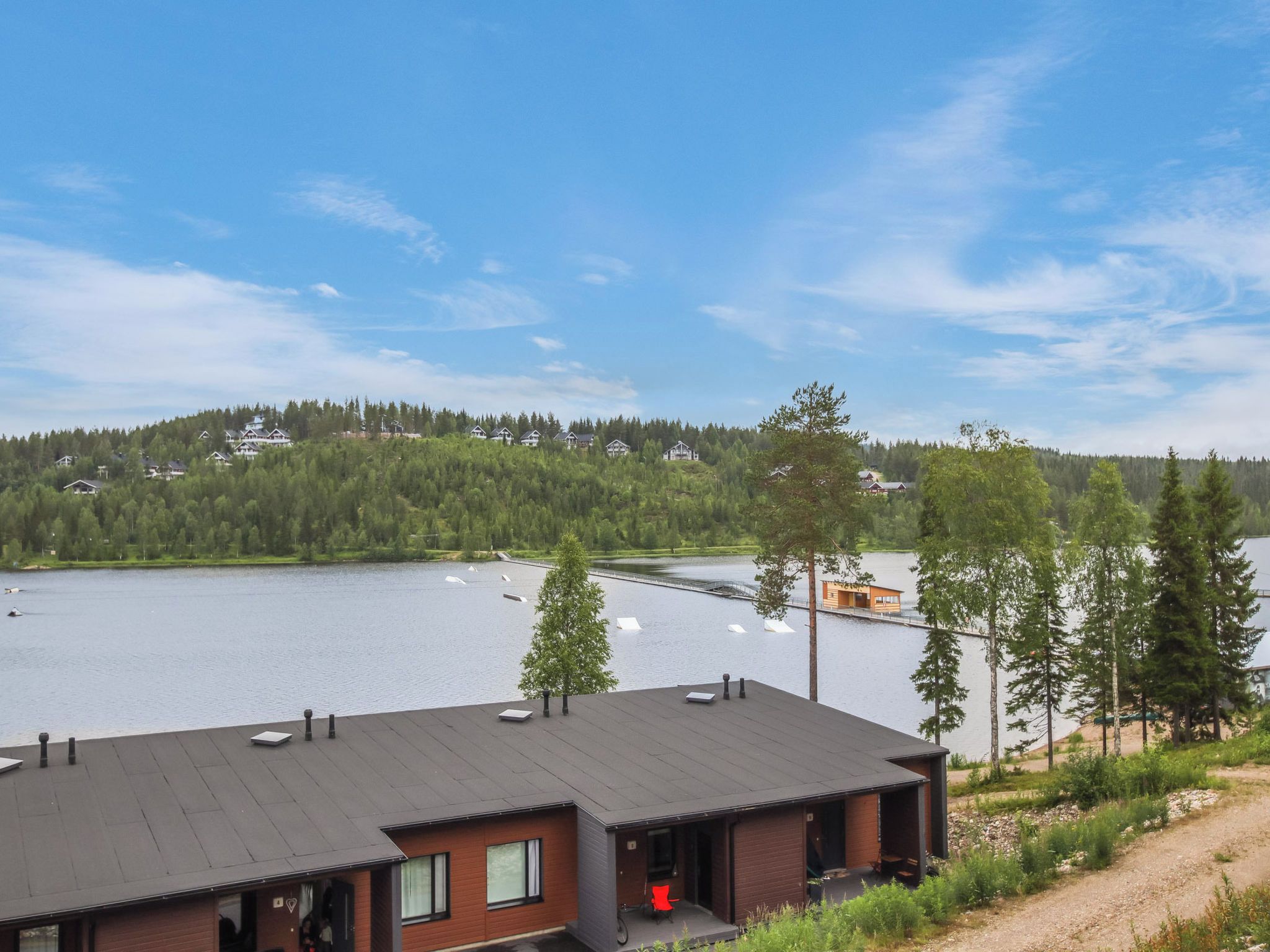 A modern building with a flat roof, a small porch, and a view of a lake with boats.