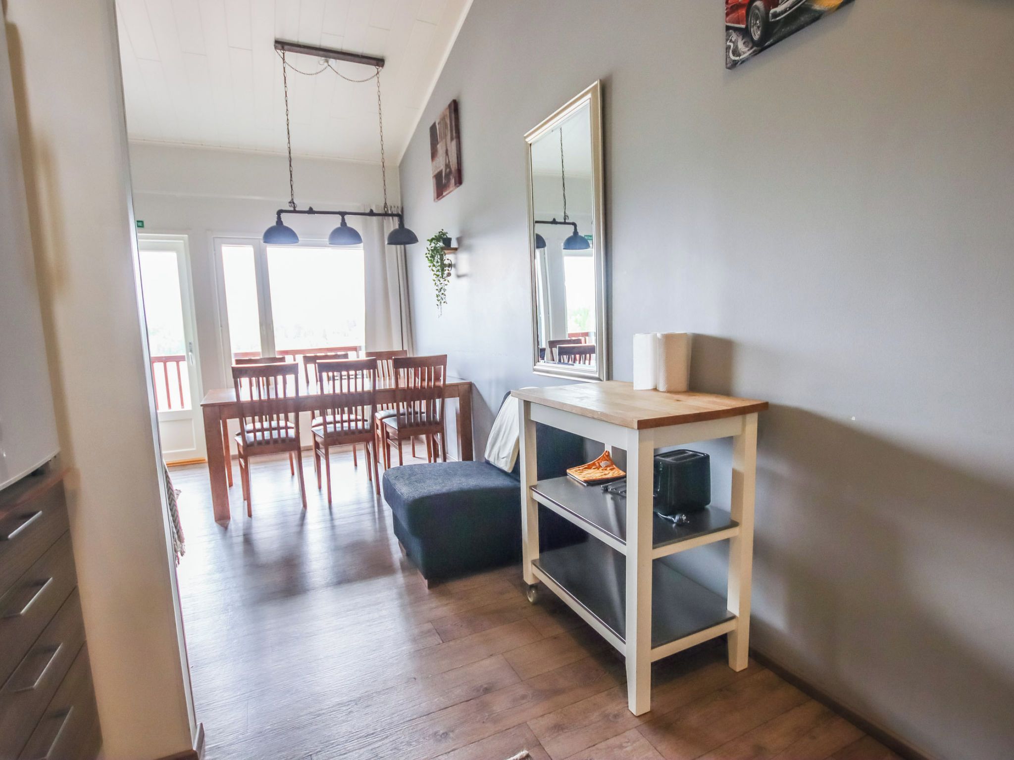 A modern kitchen with a dining area, wooden flooring, and pendant lighting.