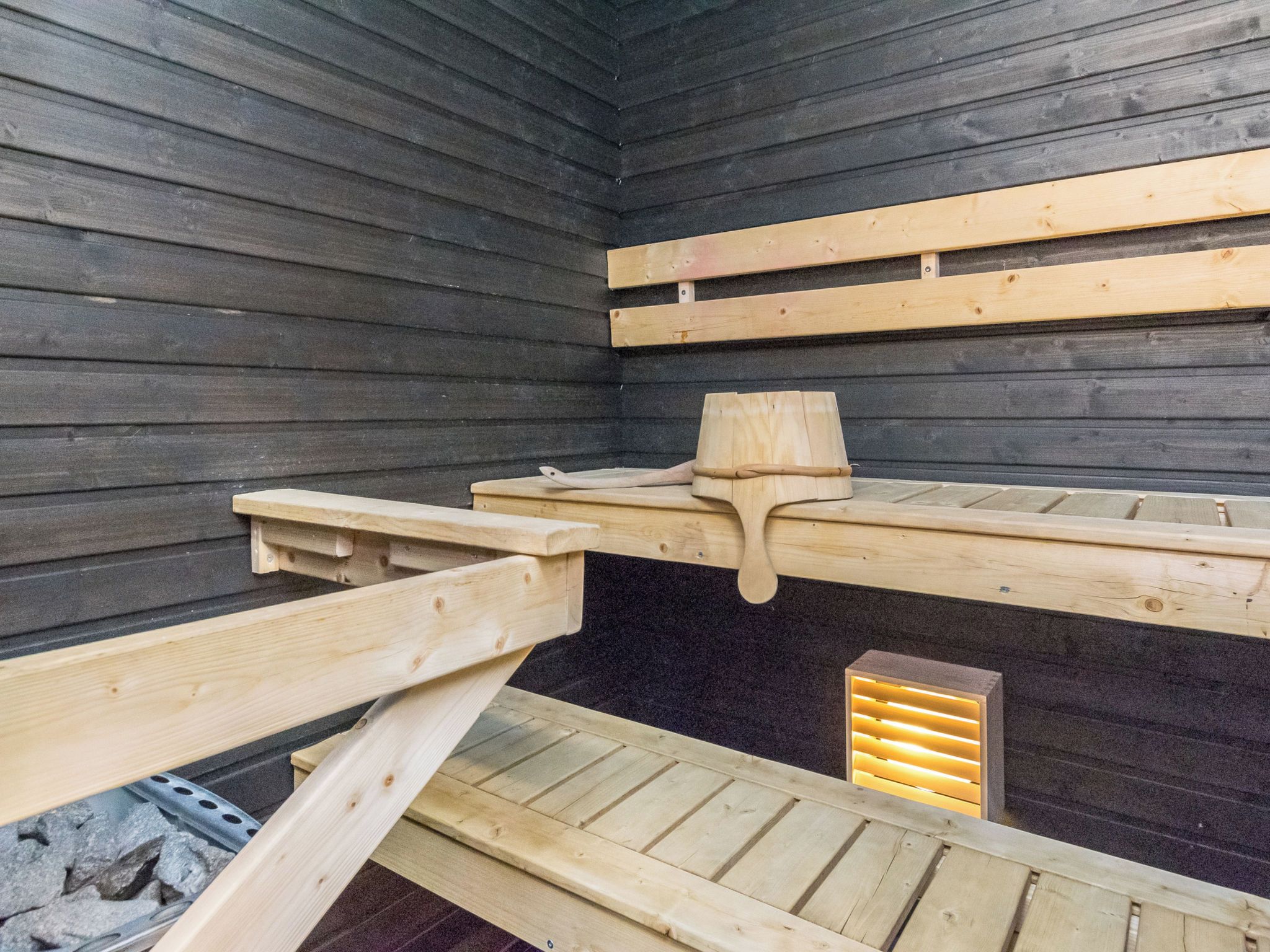 Ein Zimmer mit Holzwänden und einer geneigten Decke, mit einem Bett, einem Kopfteil und einem Nachttisch.