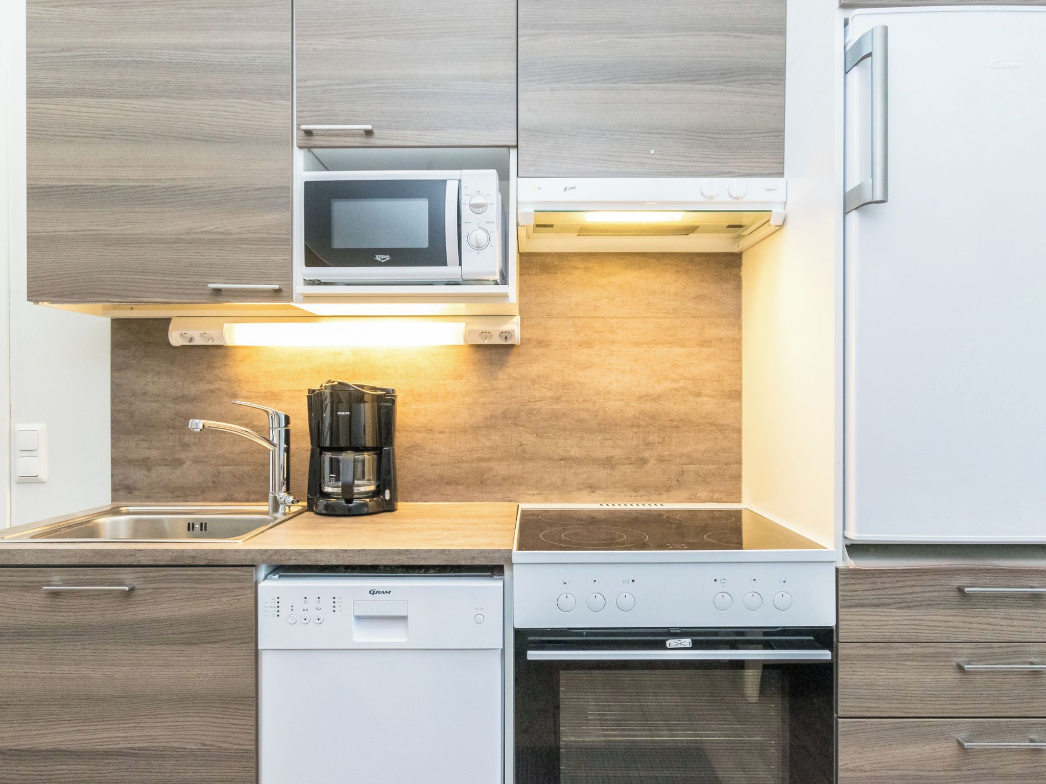 Una cocina moderna equipada con microondas, cafetera, lavavajillas y horno.