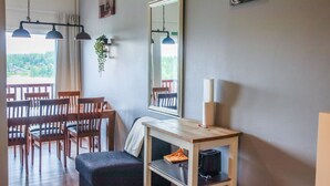 A dining area with wooden chairs and a table, a mirror on the wall, and a hanging plant. - Skivillas 61 ukkohalla (b3) by Interhome (Hyrynsalmi)