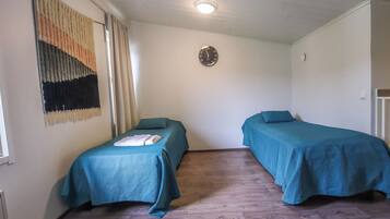 Quarto com duas camas, um relógio na parede e um tapete no chão.