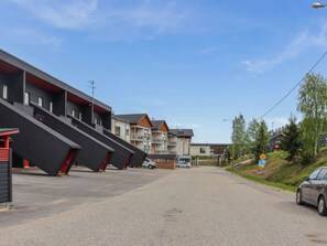 A row of modern buildings with a parking area in front.