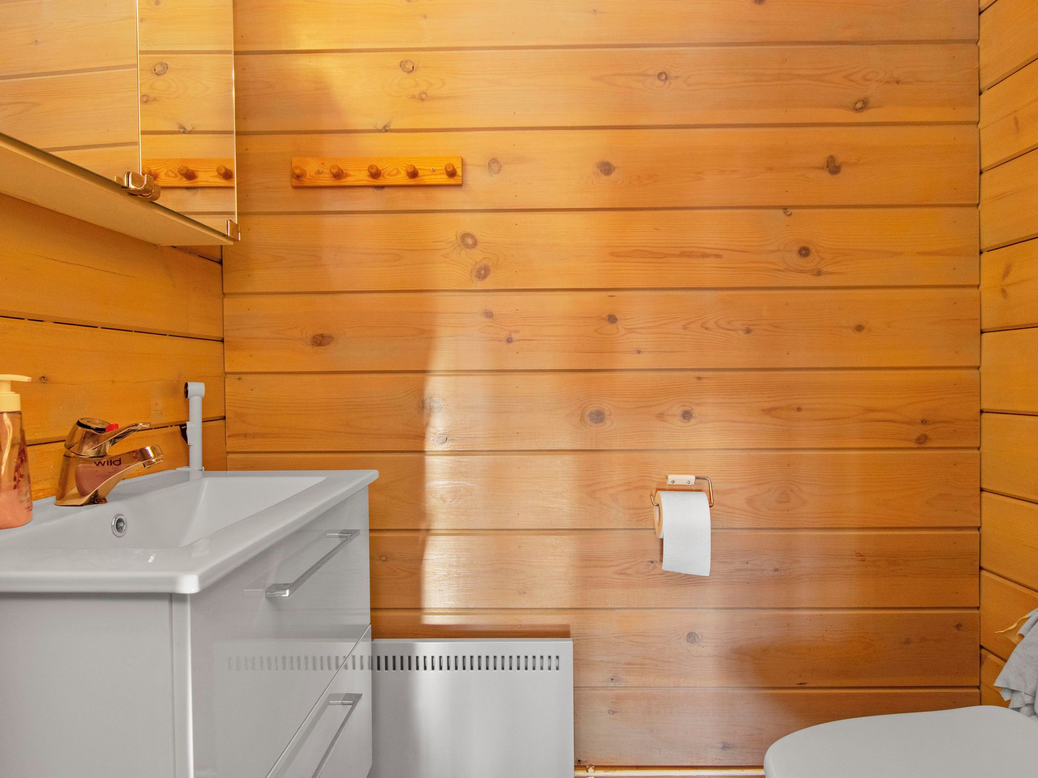 A wooden-paneled bathroom with a white sink, a toilet, and a towel rack.