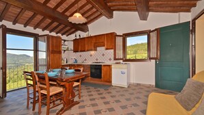 Une cuisine avec des meubles en bois, une table à manger et une vue sur l’extérieur.