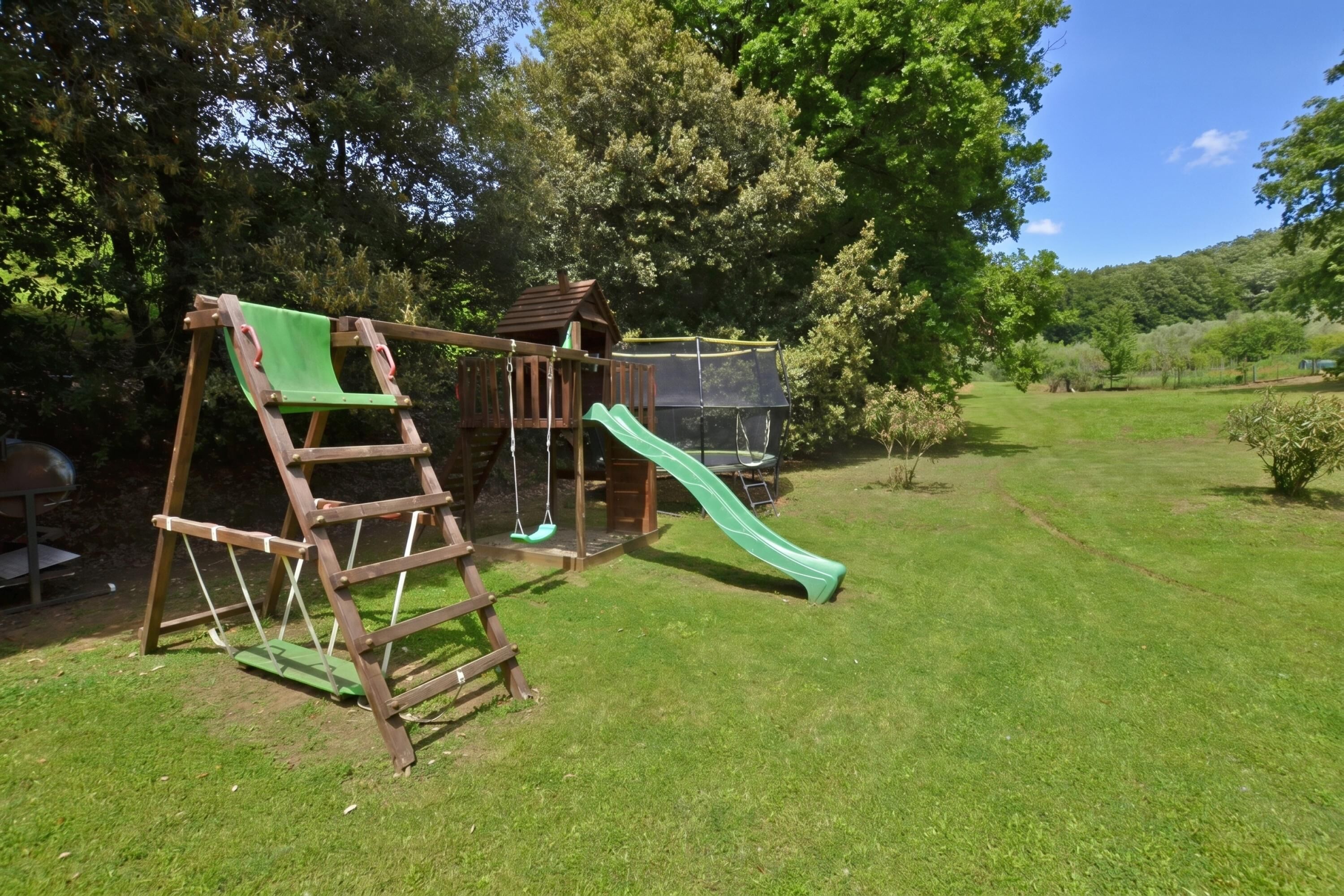 A wooden play structure with a slide and climbing area in a grassy yard.