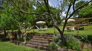 Un jardin agrémenté d’une pergola en bois, d’un espace salon extérieur et d’un toboggan.