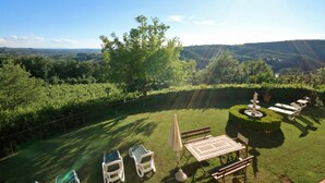 Un jardin à l’arrière de la maison, avec une table, des chaises et un espace ensoleillé.