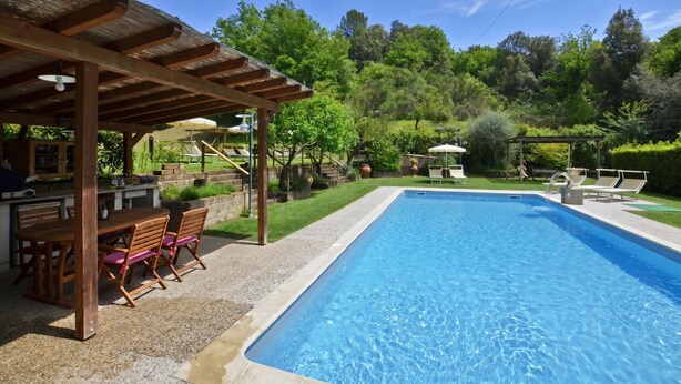 Une piscine dotée d’une pergola et d’un espace salon extérieur.