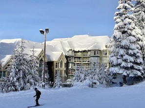 A snow-covered building with multiple windows and a ski slope in the foreground.