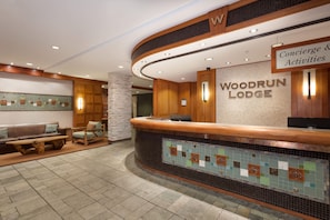 A reception area with a wooden counter, a sign for Woodrun Lodge, and a seating area with a bench and chairs.