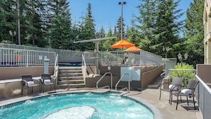 A swimming pool with steps leading into it, surrounded by lounge chairs and an orange umbrella. - Woodrun Lodge w/ pool & gym (Whistler)
