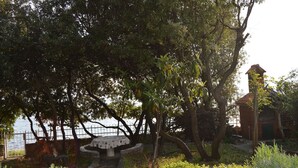 A park with a table and chairs, a fence, and a building with a red roof. - Welcome to Apartmen Palatisa (Zadar)
