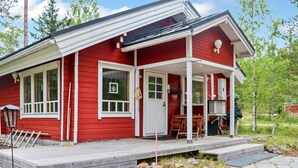 A red house with a porch, a small deck, and a window with a leaf decoration.
