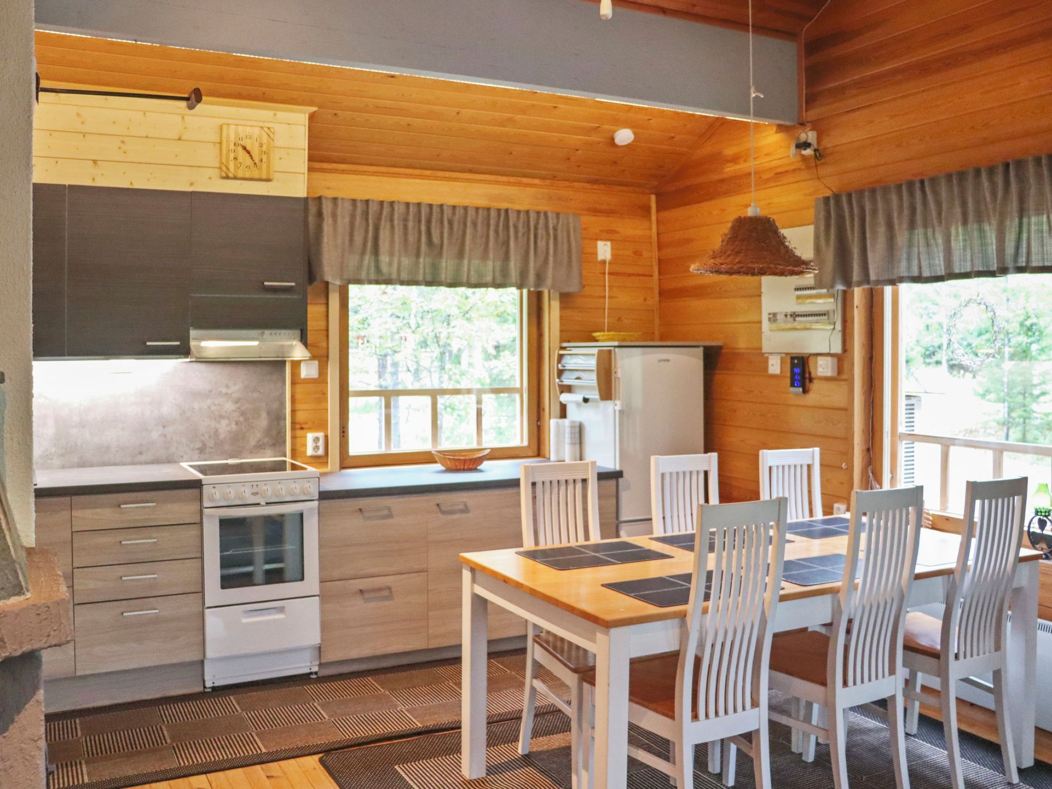 A wooden interior with a kitchen, dining table, and chairs.