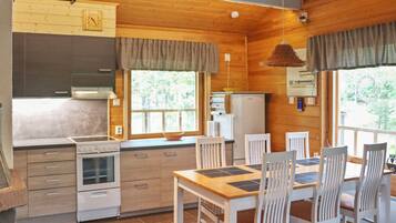 A wooden interior with a kitchen, dining table, and chairs.