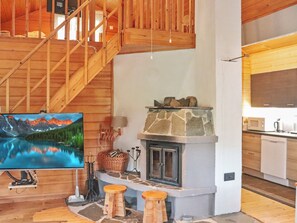 Een houten interieur met een stenen open haard, een houten trap en een keuken.