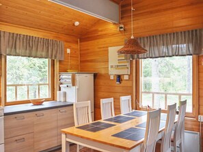 A wooden interior with a kitchen, dining table, and chairs. - Hyryn herra mökki by Interhome (Hyrynsalmi)