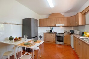 Une cuisine compacte équipée d’un réfrigérateur, d’un lave-linge, d’un four à micro-ondes, d’une cuisinière et d’un évier.