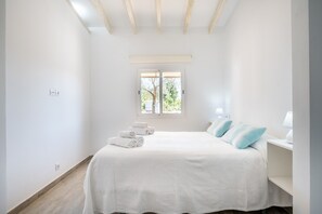 A bedroom with a bed, a window, and a bedside table. - Vacation Home Ses Oliveres with Mountain View, Wi-Fi, A/C, Terraces & Garden (Pollença)