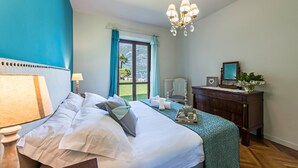 A hotel room with a bed, a desk, a chair, a dresser, and a view of the outdoors. - Holiday Apartment "La Punta Bellagio" with Lake View, Wi-Fi, Garden & Terrace (Bellagio)
