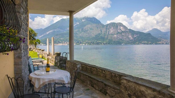 A terrace with a table set for dining, overlooking a lake with mountains in the background. - Holiday Apartment "La Punta Bellagio" with Lake View, Wi-Fi, Garden & Terrace (Bellagio)