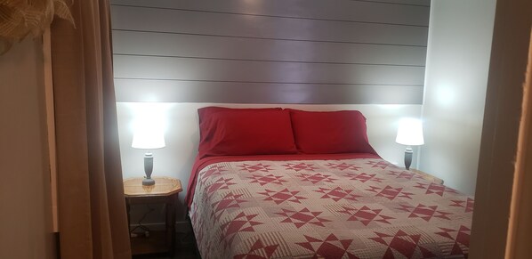 A bedroom with a bed, two bedside lamps, and a nightstand.