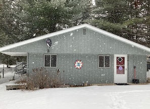 A single-story building with a gabled roof, a front door, and a small porch with steps.