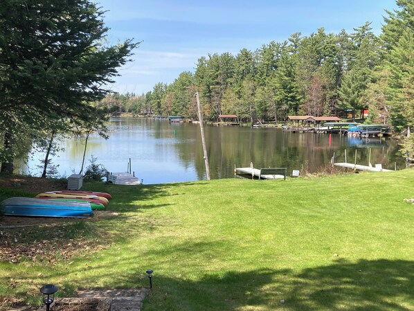 A lakeside view with boats docked, a grassy area, and a wooden dock.