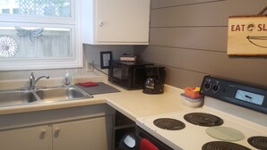 A kitchen with a sink, a coffee maker, a stove, and a sign that says "EAT & SLEEP".