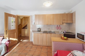 Una cocina con armarios de madera, salpicadero de azulejos, estufa y microondas.