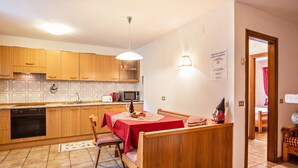 Una cocina compacta con armarios de madera, un comedor con mantel rojo y una pequeña isla.