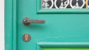 A teal door with a brass handle and a keyhole, and a decorative glass panel with heart motifs.