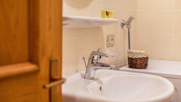 Une salle de bain avec un lavabo blanc, un miroir au-dessus et une étagère sur laquelle se trouve un distributeur de savon.