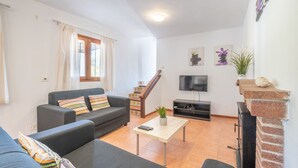 A living room with a sofa, a coffee table, a TV, and a fireplace.