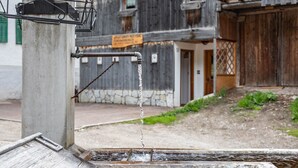 Un grifo de agua con una rejilla metálica y una pared de piedra al fondo.