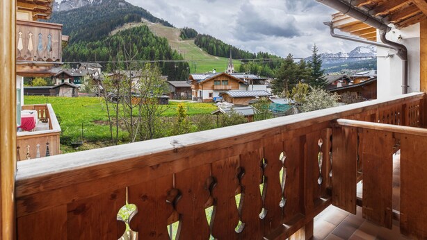 Un balcón de madera con vistas a una montaña y un pueblo.