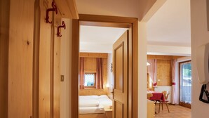 Un interior de madera con una cama, una mesa y una silla en una habitación con paredes de madera y piso de baldosas.