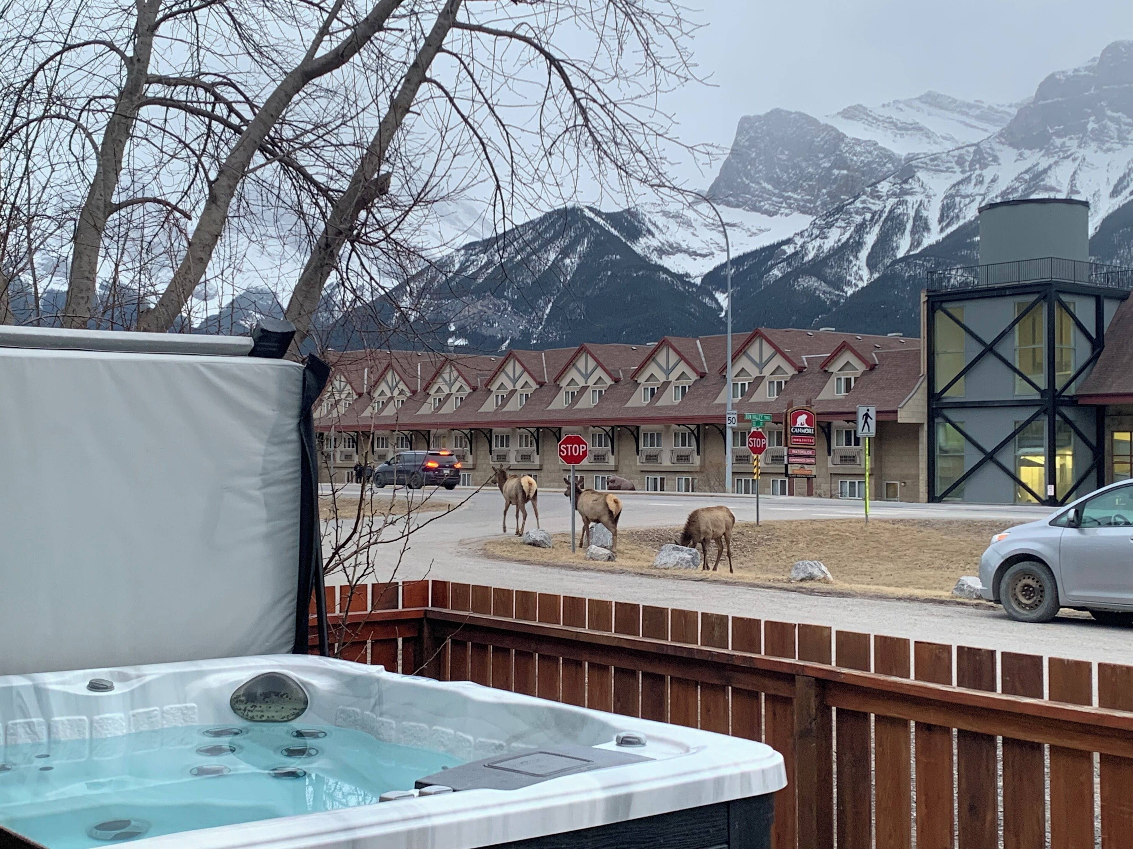 A hot tub, a building with a chalet-style roof, and a mountainous backdrop.