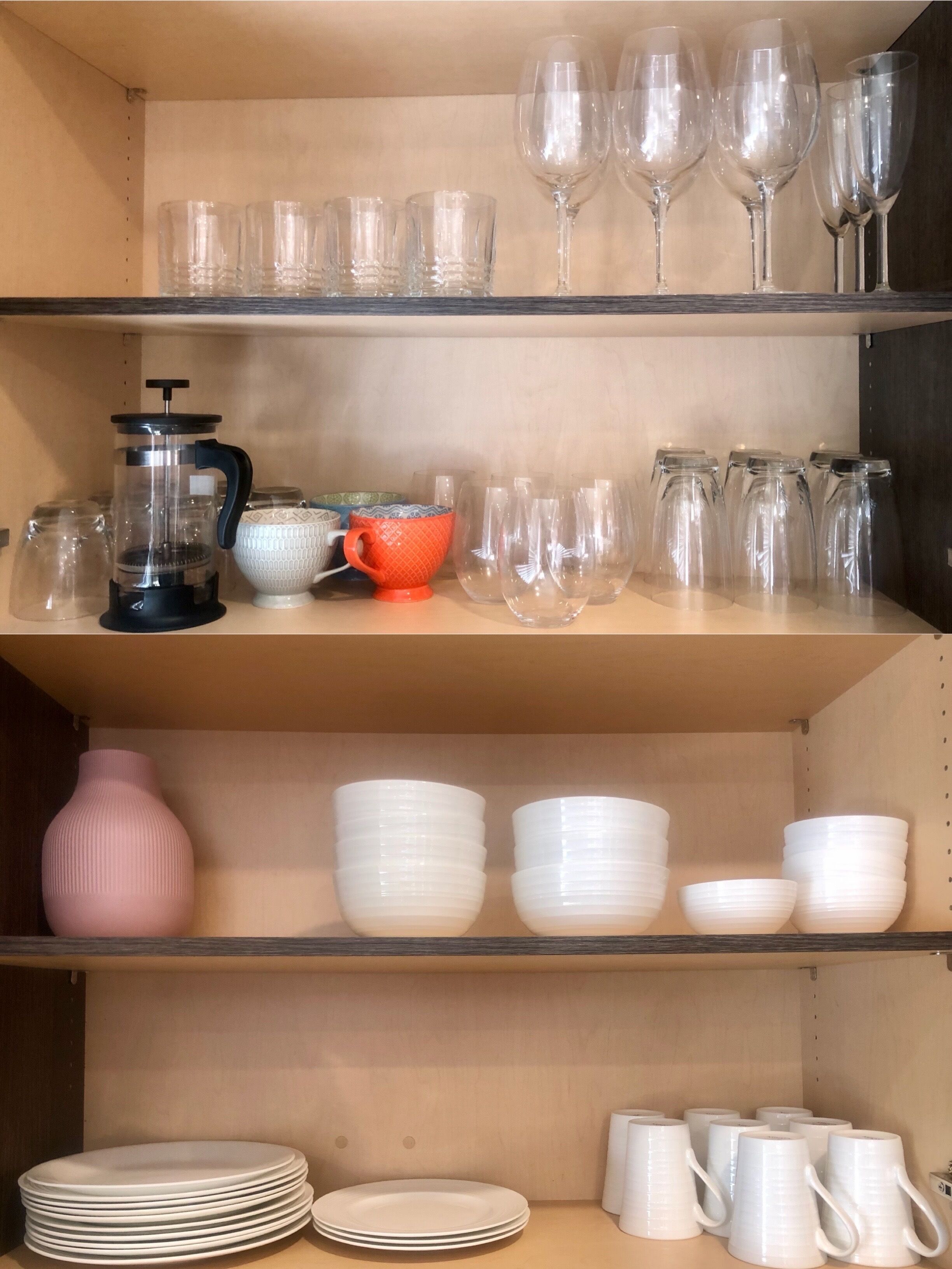 A kitchen shelf with various glassware, including wine glasses and tumblers, and a coffee maker.