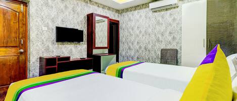 Habitación de hotel con dos camas, una puerta de madera, televisor, espejo y equipo de aire acondicionado.