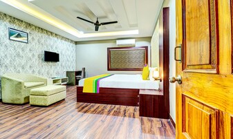 Una habitación de hotel con cama, sofá, televisor y ventilador de techo.