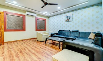 Una sala de estar con sofá, sillón, una mesa de centro y ventilador de techo.