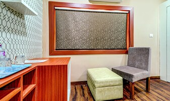 A room with a wooden desk, a cushioned bench, a patterned window, and a patterned wall.