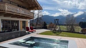 A hot tub in a wooden deck area with a view of mountains.