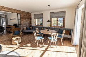 A modern living room with a wooden floor, a round wooden table, and a sofa with blue cushions.