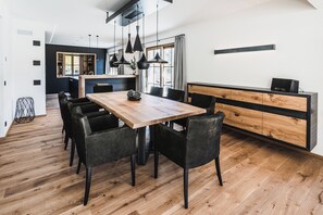 A modern kitchen with a wooden island, black chairs, and pendant lighting.