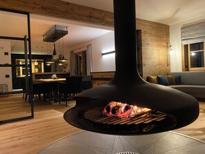 Una cucina moderna con un camino a legna al centro, un'area pranzo con sedie e una parete in legno.