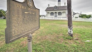Een historiek bord voor Vuurtoren Tybee, met een wit gebouw en een vuurtoren op de achtergrond.